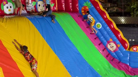Thai Children Playing on Large Inflatable Slide at Night Carnival Stock Footage 327691722