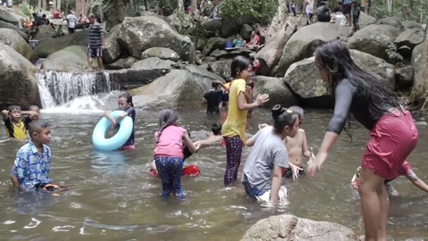 Thai children playing in waterfall pool big rocks happy kids enjoying swim Stock Footage 157446655