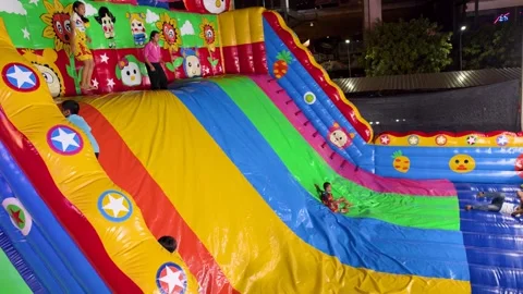 Thai Children Sliding Down Large Colorful Inflatable Slide at Night Carnival Stock Footage 327637751