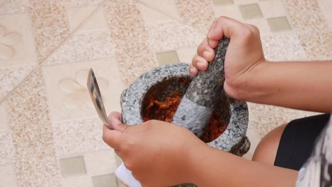 Thai chilli and garlic pounding in stone mortar with pestle. Woman preparing Stock Footage 106224527