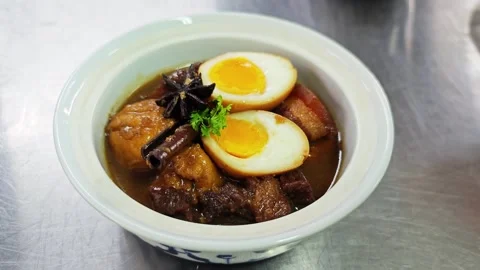 Thai-Chinese five-spice egg stew with pork belly served in a white bowl. Vidéo 344658789