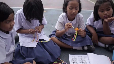 Thai cute little students making knitting colorful rubber band bracelet Stock Footage 157059946
