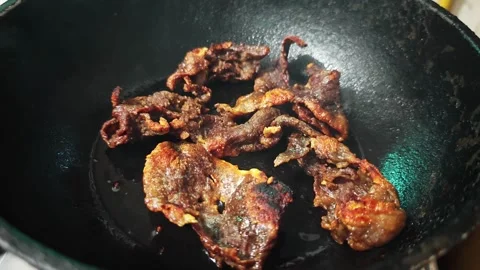 Thai deep-fried sun-dried beef or fried salted beef strips in a black wok. Stock Footage 347633037