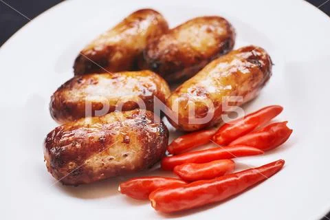 Thai food, pork sausage grilled with red chilies on white plate. Stock Photos