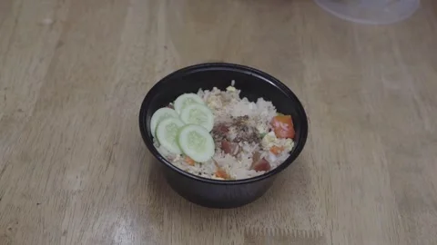 Thai fried rice topped with fresh cucumber slices, egg, and vegetables in a.. Video stock 337623157
