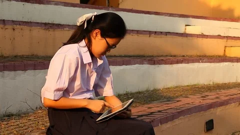 Thai girl student using tablet and siting at the park Stock Footage 75158017