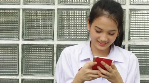 Thai high school student uniform teen beautiful girl using her phone and smile Stock Footage 68335544
