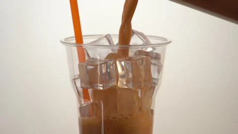 Thai iced tea poured into clear cup with orange straw and ice Stock Footage 318844075