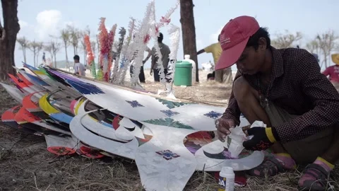 Thai kite festival kiter fixing his traditional paper hand made Wau Bulan Kite Stock Footage 157448732