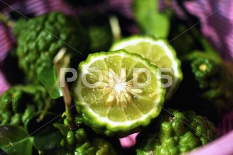 Thai limes with wrinkled skin, whole and halved Stock Photos