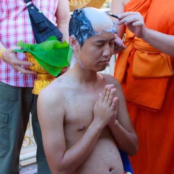 Thai man gets his head shaved by a monk during a Buddhist ordination ceremony Stock Photos