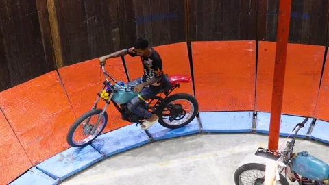 Thai Man Performs Motorcycle Stunts Inside a Wooden Wall of Death 動画素材 327446366