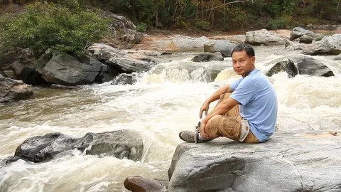 Thai man sitting on the rock and waving hand  in Ob-khan national park Chiangmai Stock Footage 101215575