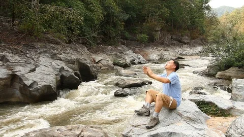 Thai man sitting on the rock and cheerful in Ob-khan national park Chiangmai Tha Stock Footage 101216093