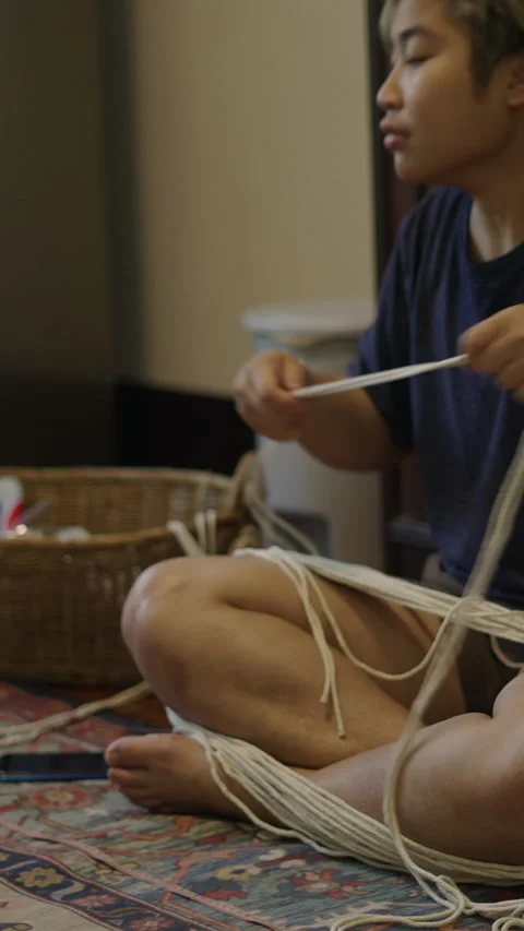 Thai man stringing together pieces of yarn Stock Footage 265494282