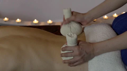 Thai masseuse does a back massage with herbal bags to a woman close-up Stock Footage 223205609