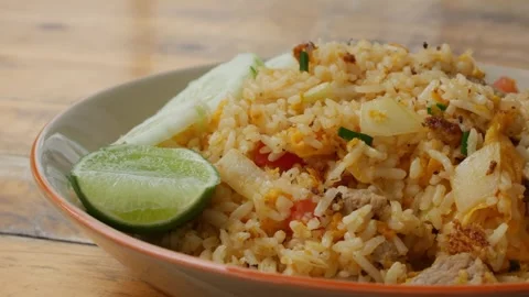 Thai Pork Fried Rice with Cucumber Slices and Lime on Rustic Wooden Table Stock Footage 343234258