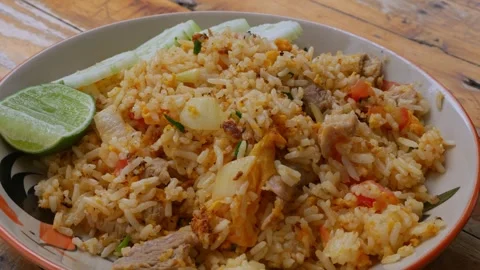 Thai Pork Fried Rice with Cucumber Slices and Lime on Rustic Wooden Table Stock Footage 343609912