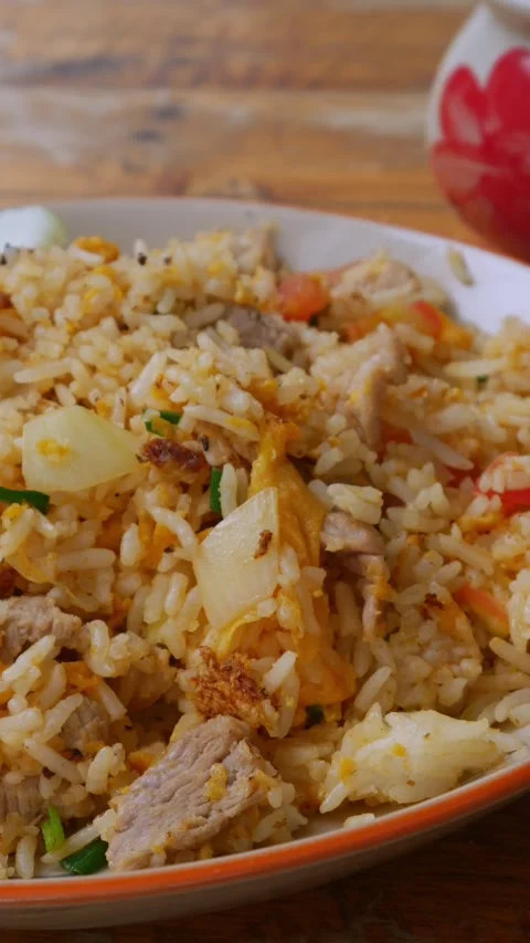 Thai Pork Fried Rice with Cucumber Slices and Lime on Rustic Wooden Table Stock Footage 343609917