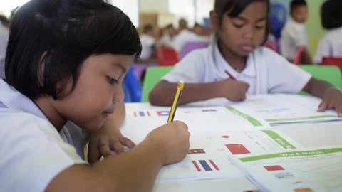 Thai primary students study English language in classroom writing in test book Stock Footage 156870421
