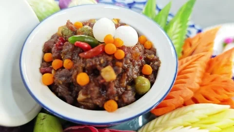 Thai spicy chili paste Nam Phrik Long Ruea with carved vegetables close-up. Stock Footage 343210283