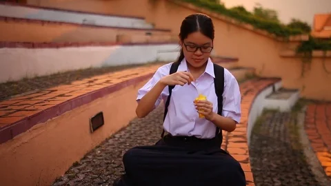 Thai student girl blowing bubbles at park Stock Footage