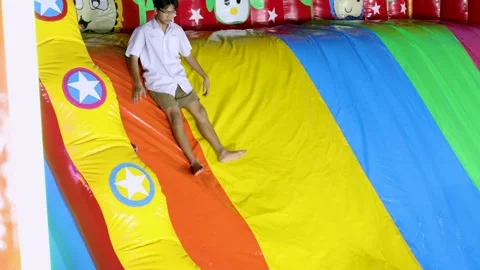 Thai Student in School Uniform Sliding Down Colorful Inflatable Bounce House Stock Footage 328063707