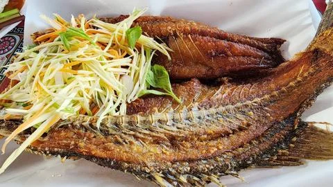 Thai Style Crispy Deep Fried Sea Bass Served with Spicy Green Mango Salad Stock Photos