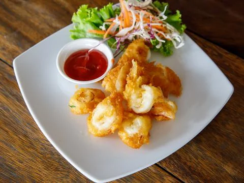 Thai style deep fried squid rings tempura on white plate with tomato chili sa Foto stock