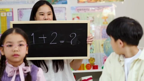 Thai Teacher Holding Chalkboard with Math Equation for Elementary Students Stock Footage 328208726