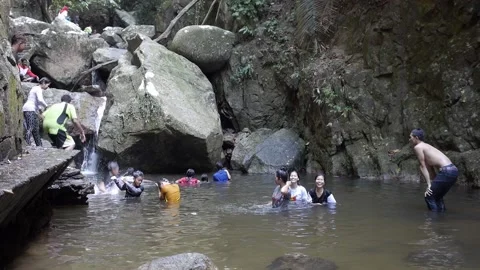 Thai teens playing in the waterfall big rocks smiley happy girls wave to camera Stock Footage 157326718
