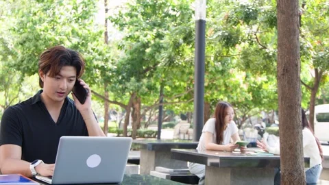 Thai University Student Using Laptop and Talking on Phone Outdoors Stock Footage 329010772