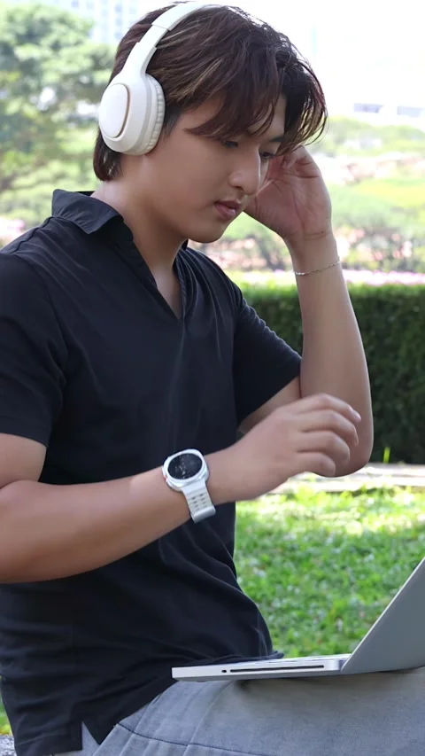Thai University Student Using Laptop and Headphones Outdoors in Bangkok Vídeo Stock 330450949
