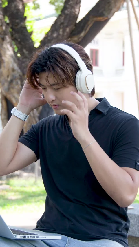 Thai University Student Using Laptop and Headphones Outdoors on Campus Stock Footage 335192518