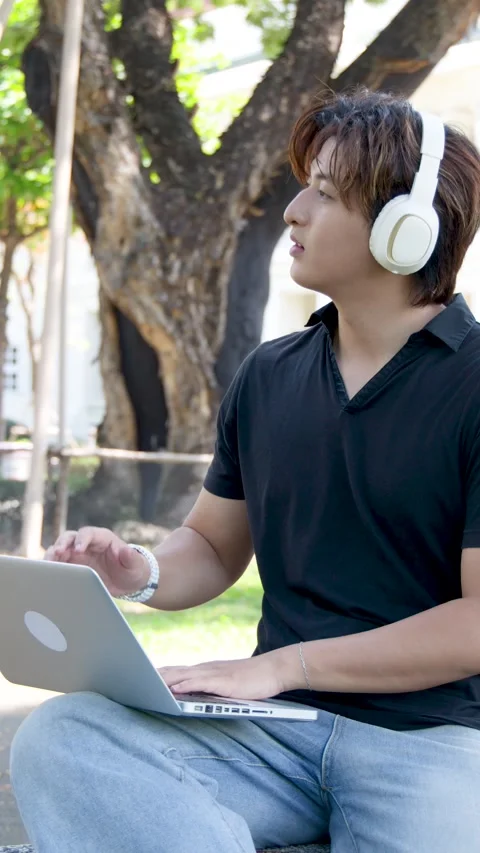 Thai University Student Using Laptop with Headphones on Campus Outdoors Stock Footage 336352218