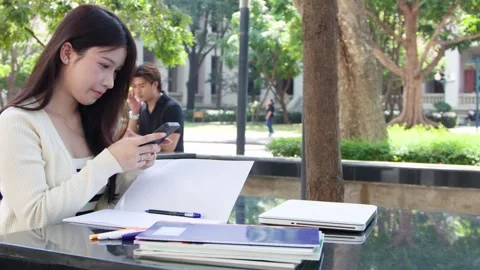 Thai University Student Using Smartphone While Studying Outdoors in Bangkok Stock Footage 328786493