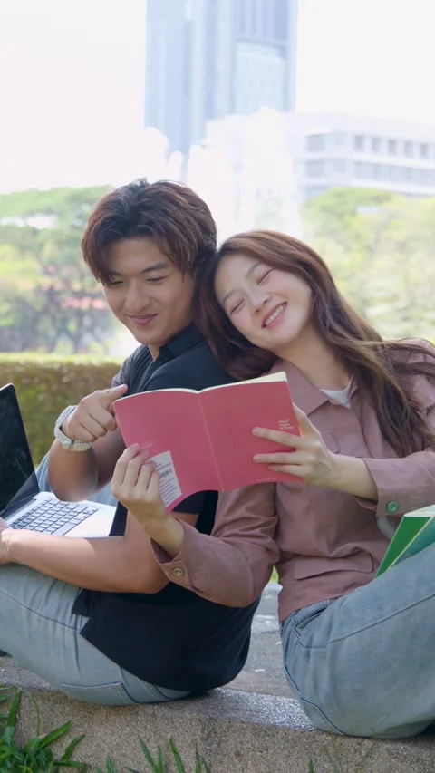Thai University Students Reading Book and Using Laptop in Campus Park Stock Footage 335455624