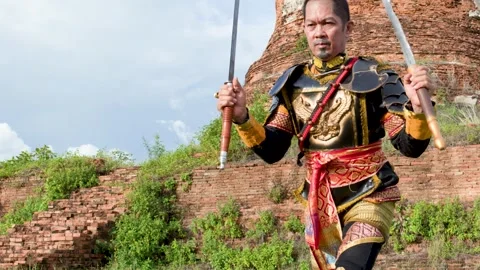 Thai Warrior in Ancient Armor Performing Sword Skills at Historical Ruins Stock Footage 338319639