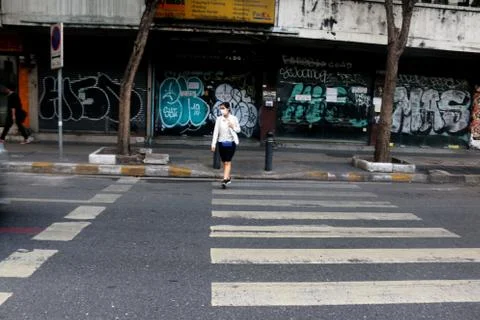 Thai woman with Corona mask crossing an empty street on a crosswalk. Stock Photos