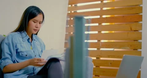 Thai womansitting on sofa, looking and worry about bill paper Stock Footage 135659699