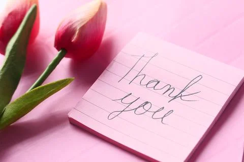 Thank you message on sticky note with tulip flower on pink background Stock Photos