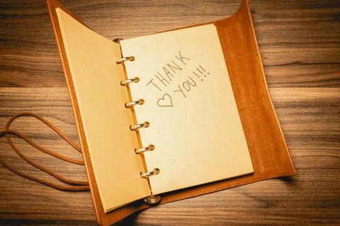 A thank you note  in a leather notebook, on a wooden background Stock Photos