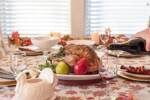 Thanksgiving dinner table, man pouring wine in foreground Stock Photos
