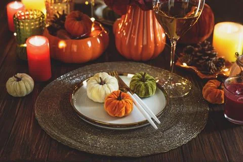 Thanksgiving table setting with decorative pumpkins, candles and string light Фото