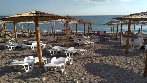 Thatch umbrellas and beds on the beach - tiki straw parasols Stock Footage 212518014