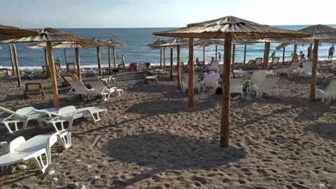 Thatch umbrellas and beds on the beach - tiki straw parasols Stock Footage 212531155
