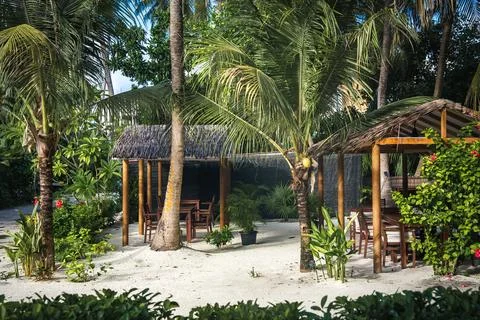Thatched dining gazebos surrounded by palms in Maldives Stock Photos