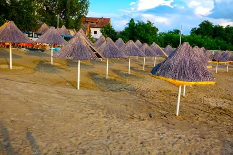 Thatched sunshades on the empty sandy beach Stock Photos