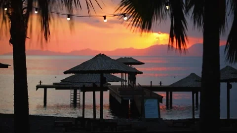 Thatched umbrellas and sunset behind the wooden pier, defocus. Stock Footage 247314921
