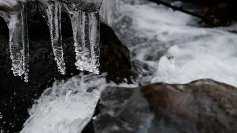 Thaw of icicles on the river, water running hard Stock Footage 148243561
